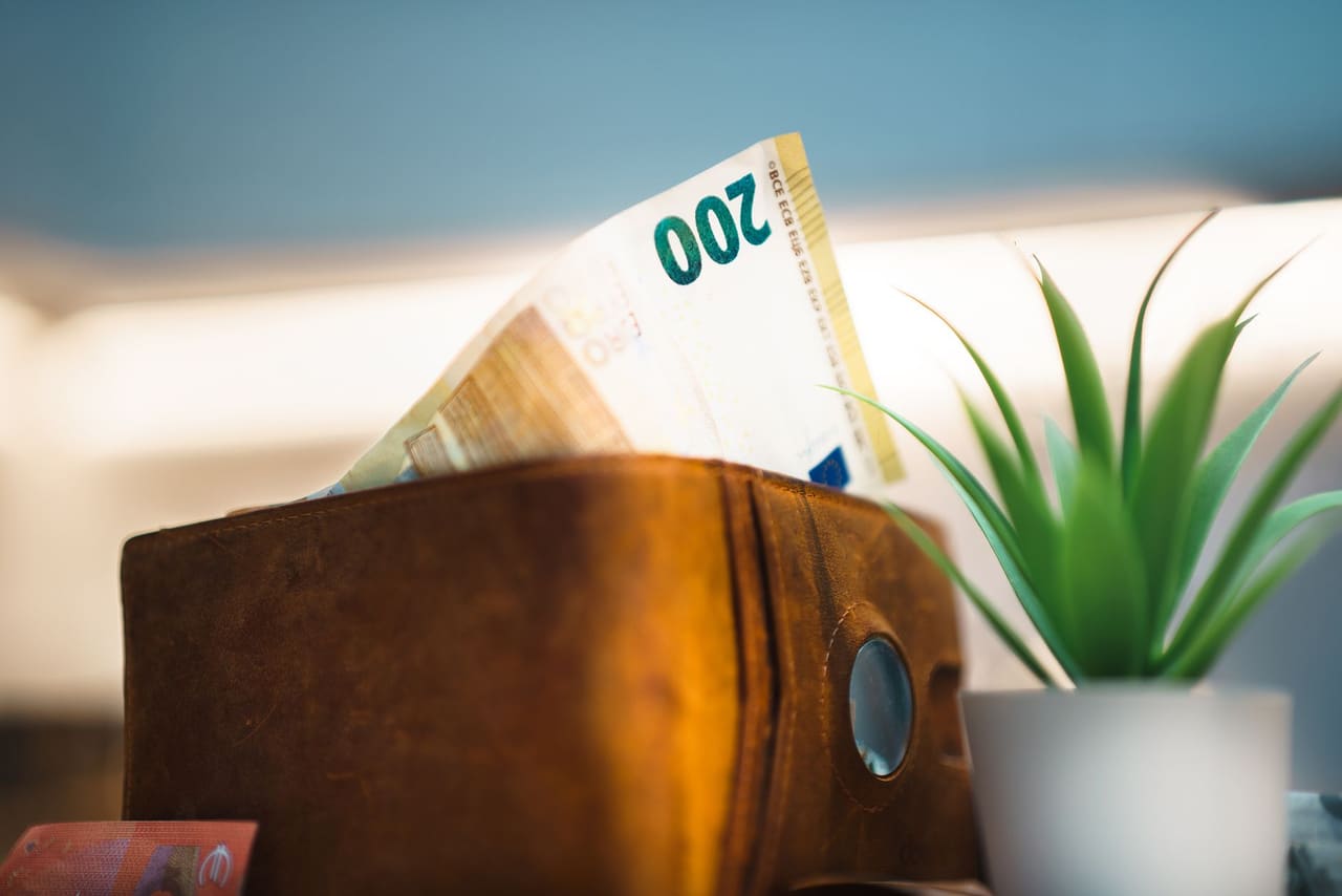 A euro banknote tucked into a leather wallet