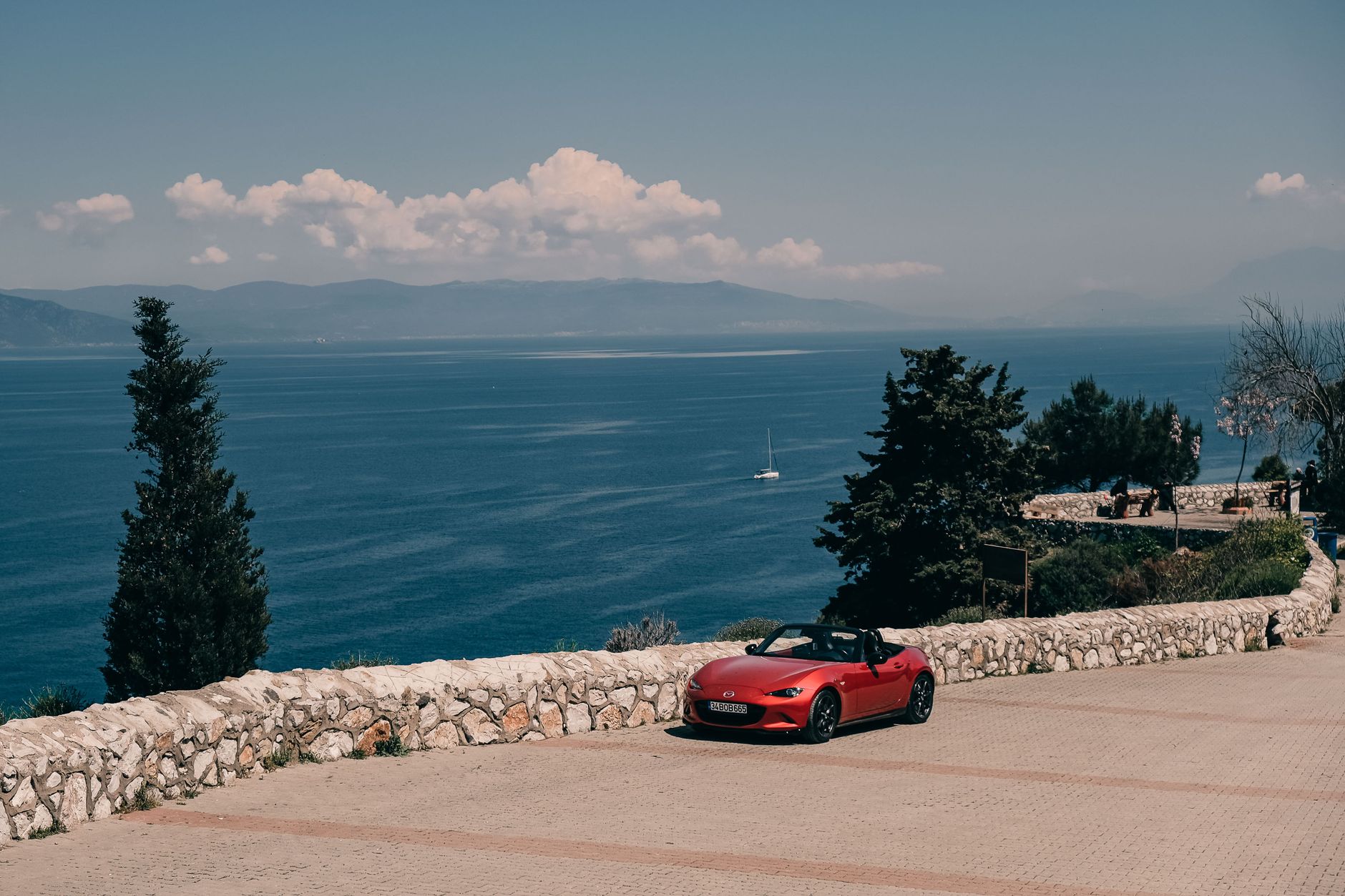 Convertible car on a Mediterranean coastal road above turquoise water