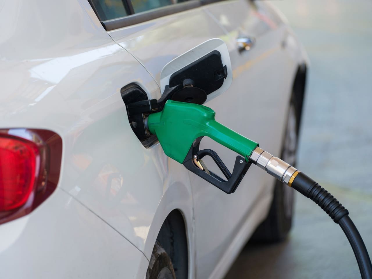 A green fuel nozzle refuelling a car