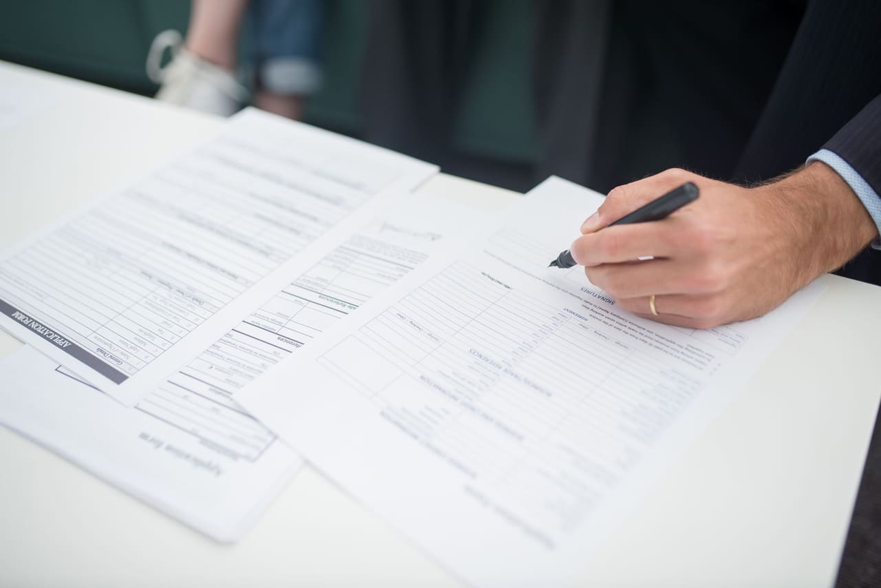 A hand filling in insurance forms