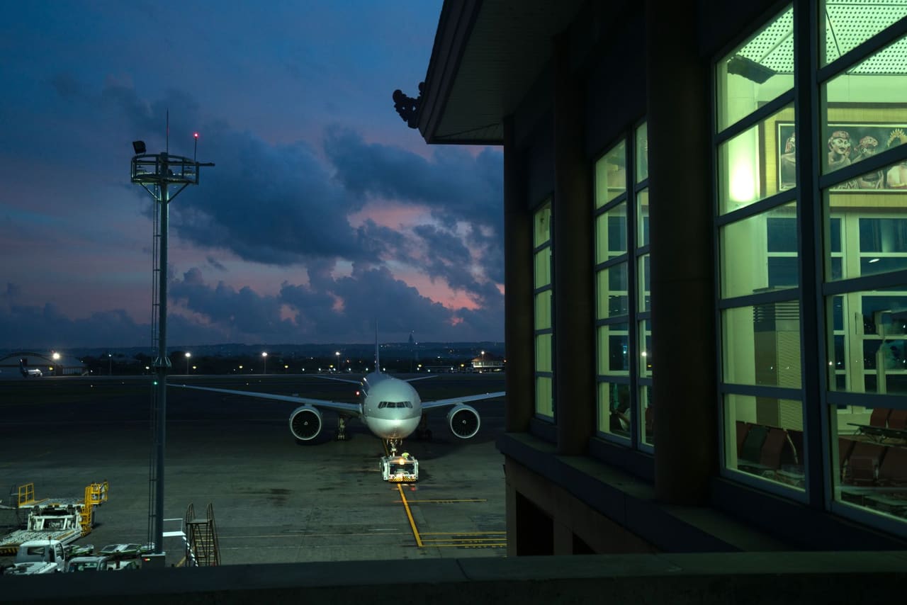 An airliner on its stand beside the terminal at dusk