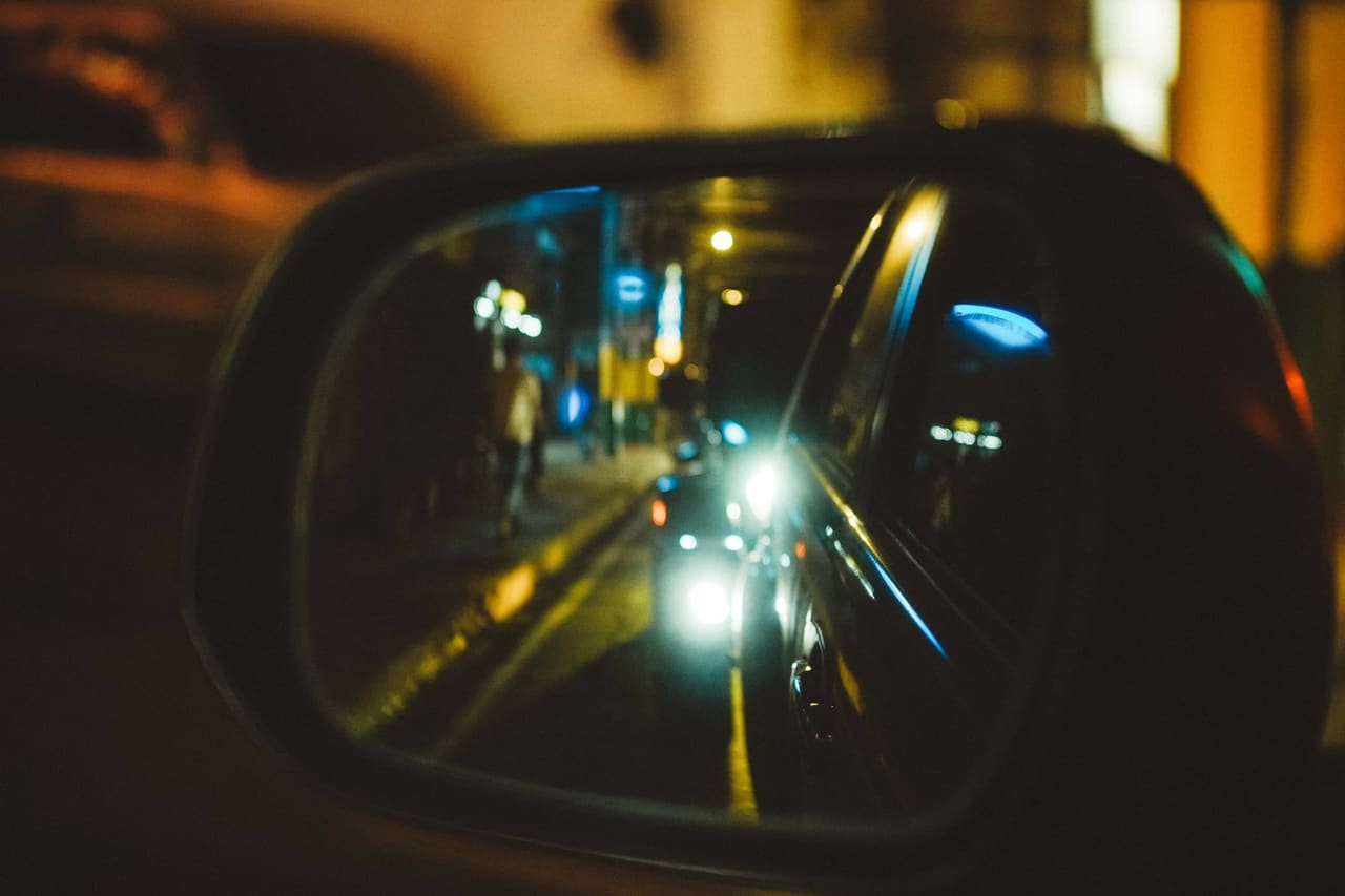 Gece, araç yan aynasında şehir ışıkları