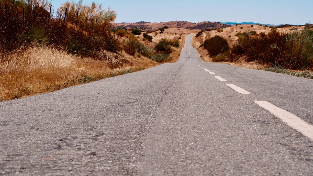Kurak tepeler arasında uzanan boş asfalt yol